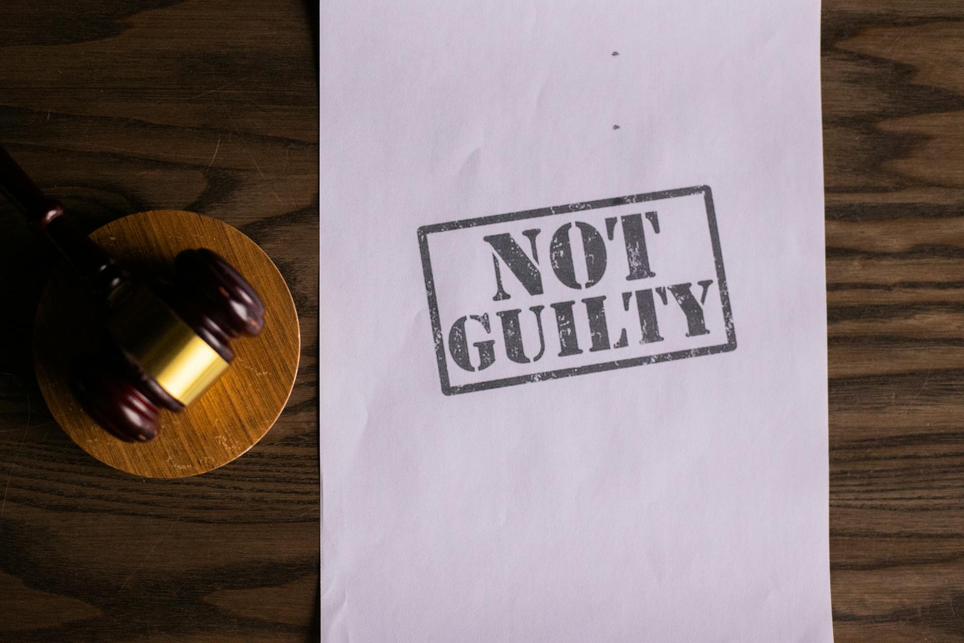 Młotek sędziowski obok dokumentu z napisem Not Guilty na biurku