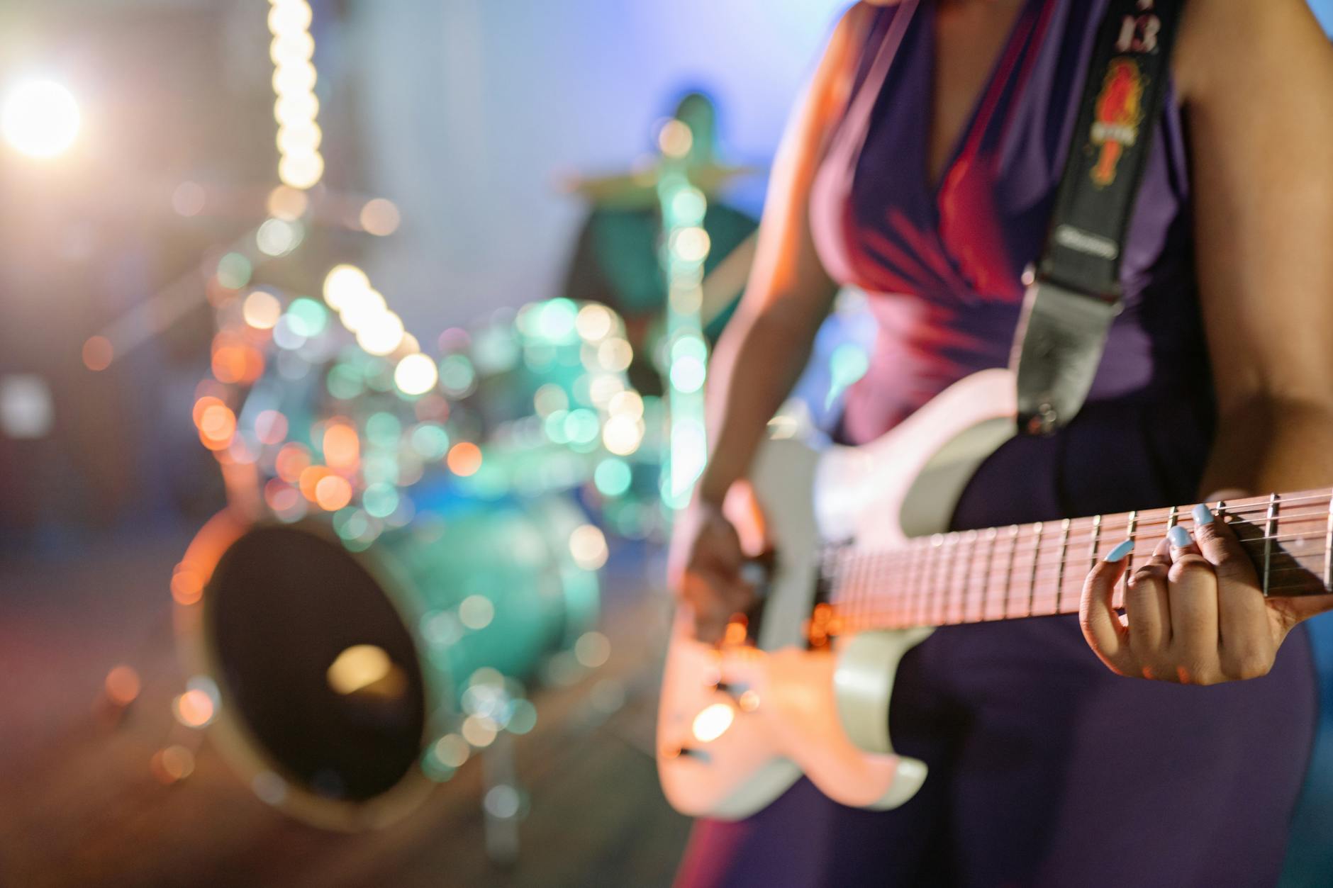 Gitarzystka rockowa na scenie, w tle perkusja
