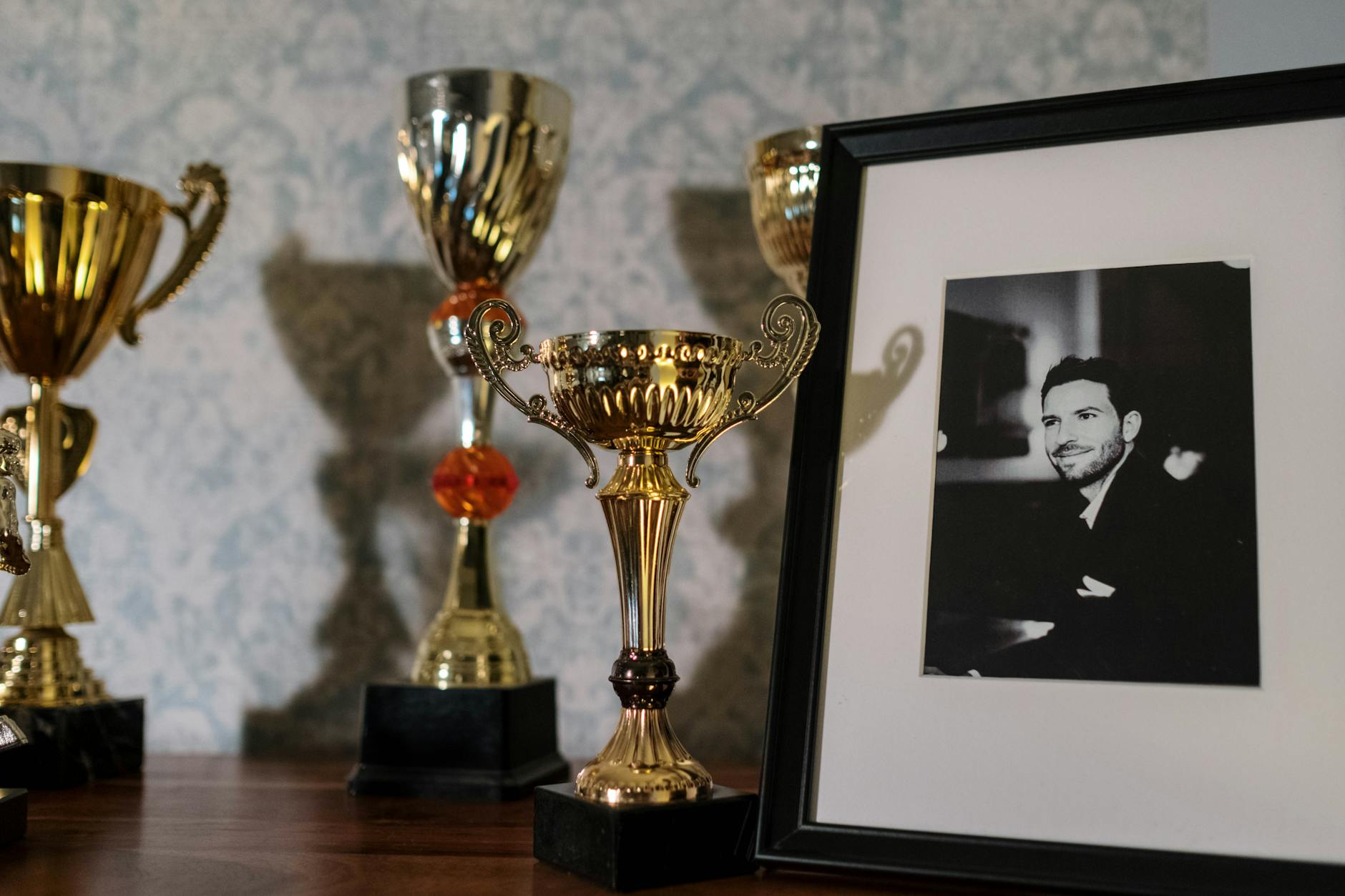 Półka z wieloma trofeami i czarno-białym portretem w ramce
