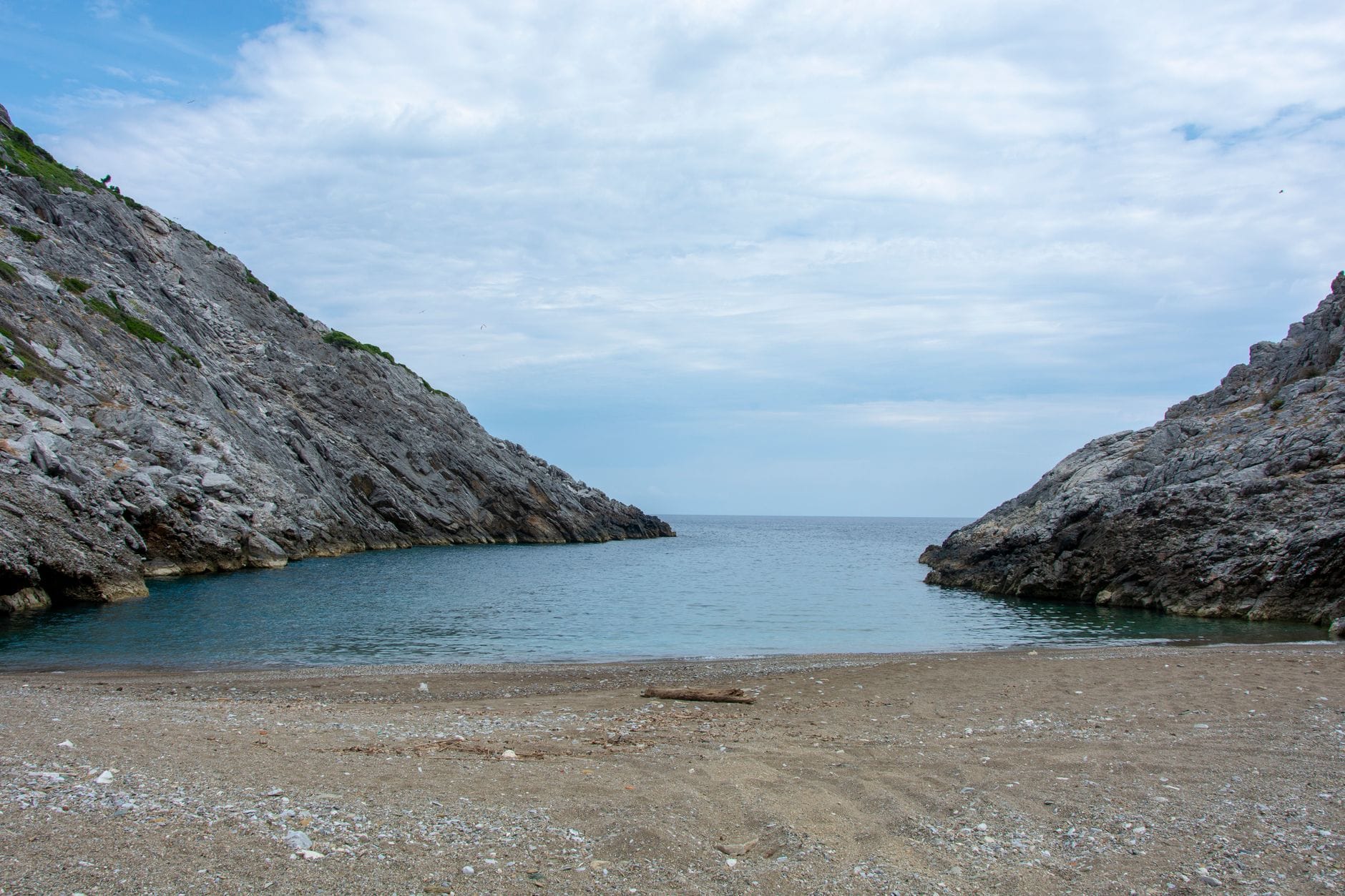 Spokojna, pusta plaża nad jeziorem otoczona skalistymi klifami